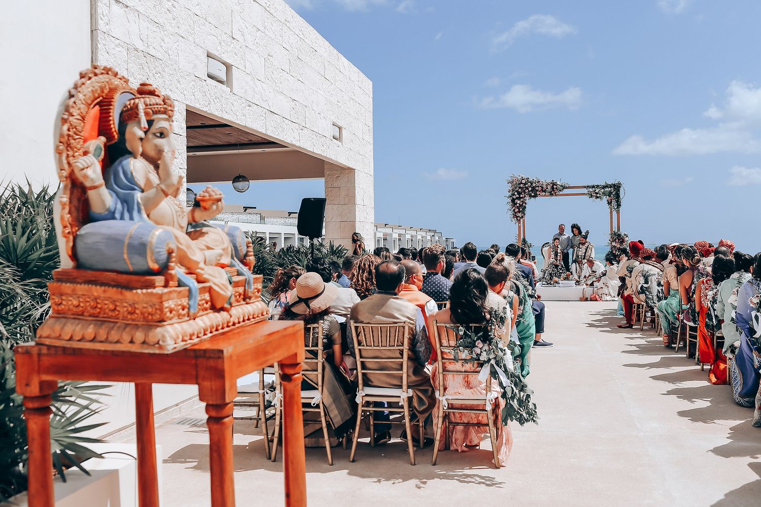 Outdoor wedding reception setup with orange throne chair and ocean view.