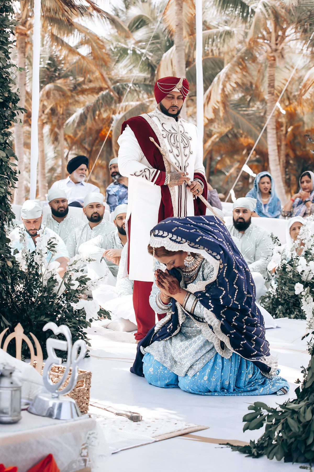 Traditional wedding ceremony participants performing cultural rituals with blue and burgundy accents.