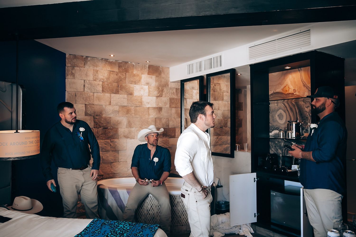 A casual gathering of people in a modern room with stone walls and artwork.
