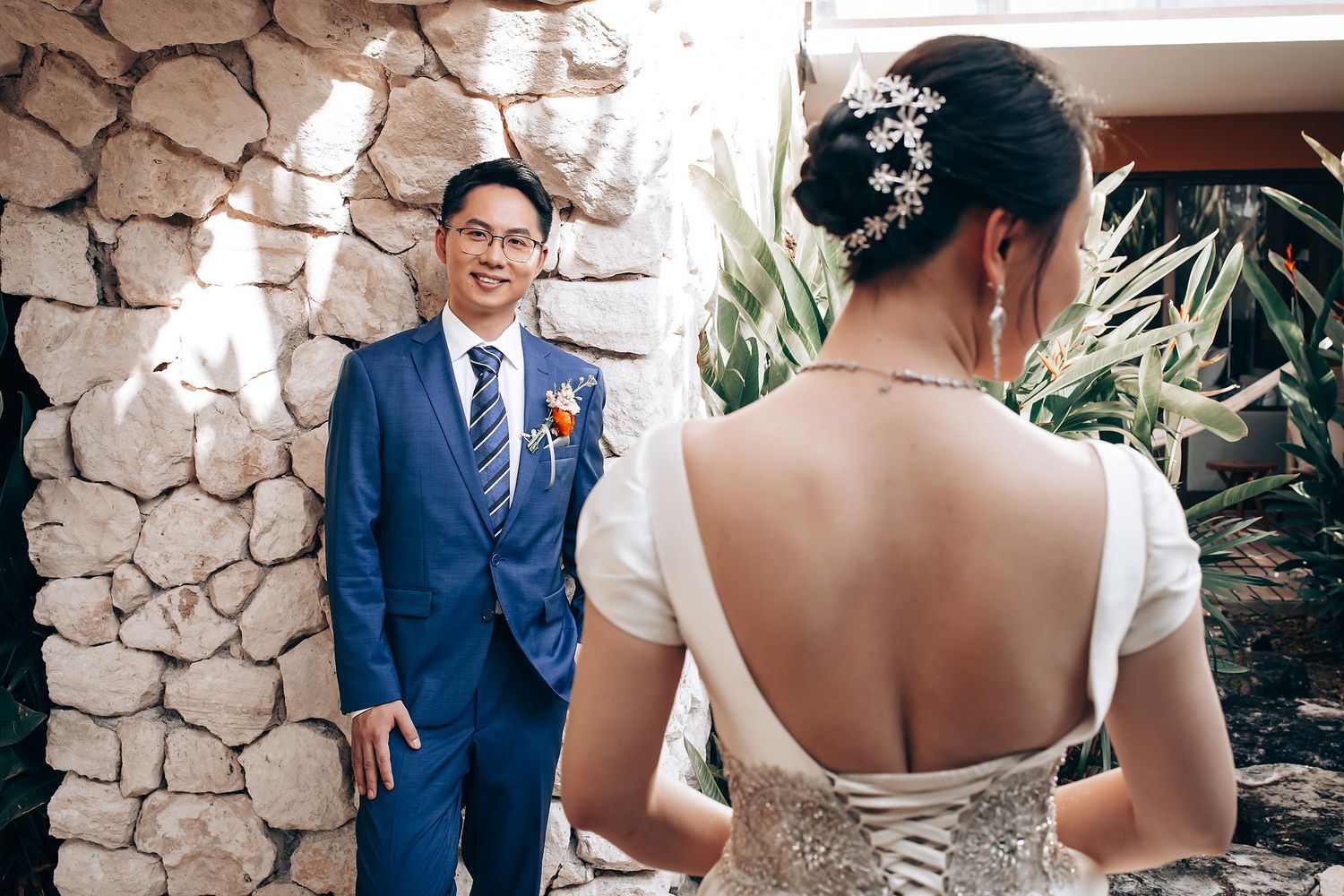 Romantic wedding first look moment against a rustic stone wall backdrop with natural lighting.