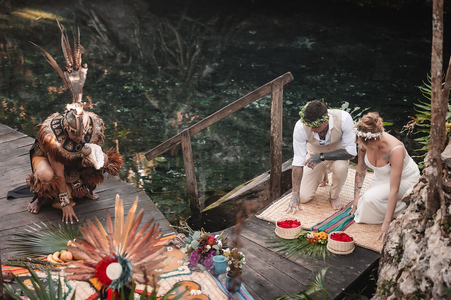 A traditional ceremony being performed in a lush outdoor setting with natural stone features.