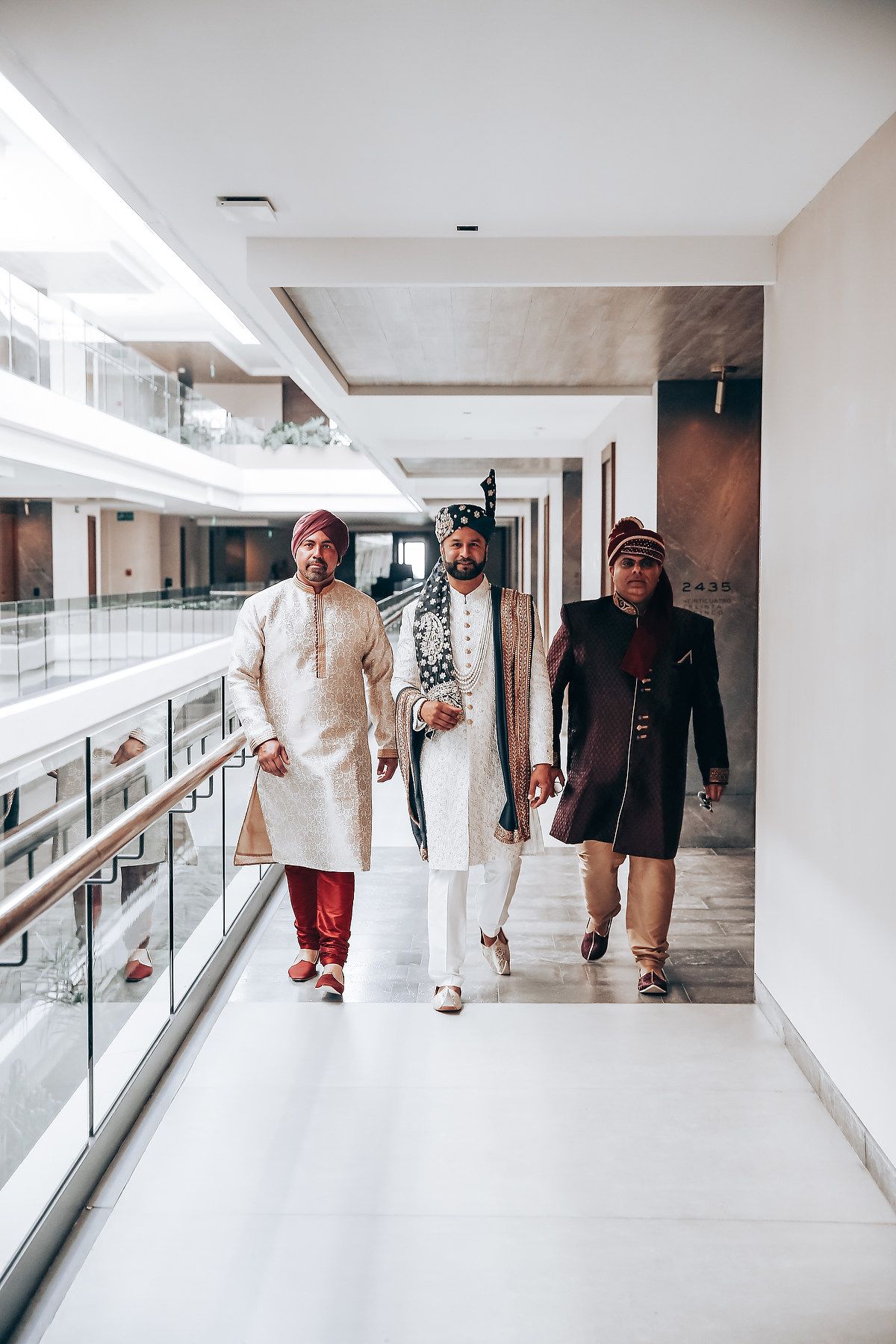 People walking down a bright modern hallway with glass railings and white walls in a medical or office building.
