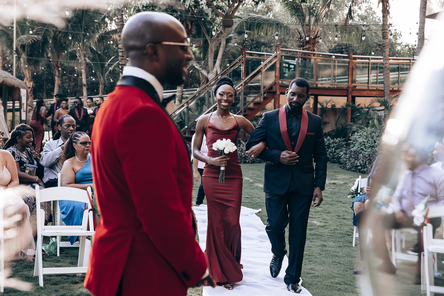 Wedding guests gather outdoors at a garden celebration with string lights and decorative elements.