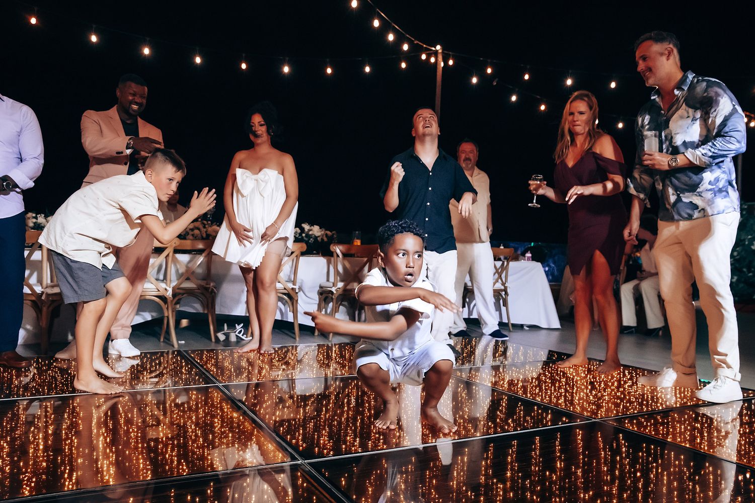 Wedding reception dance floor filled with celebrating guests under twinkling lights.