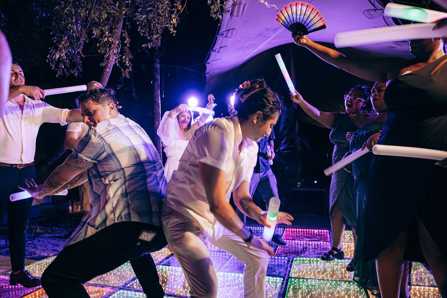 People dancing energetically on a purple-lit dance floor at a festive evening event.