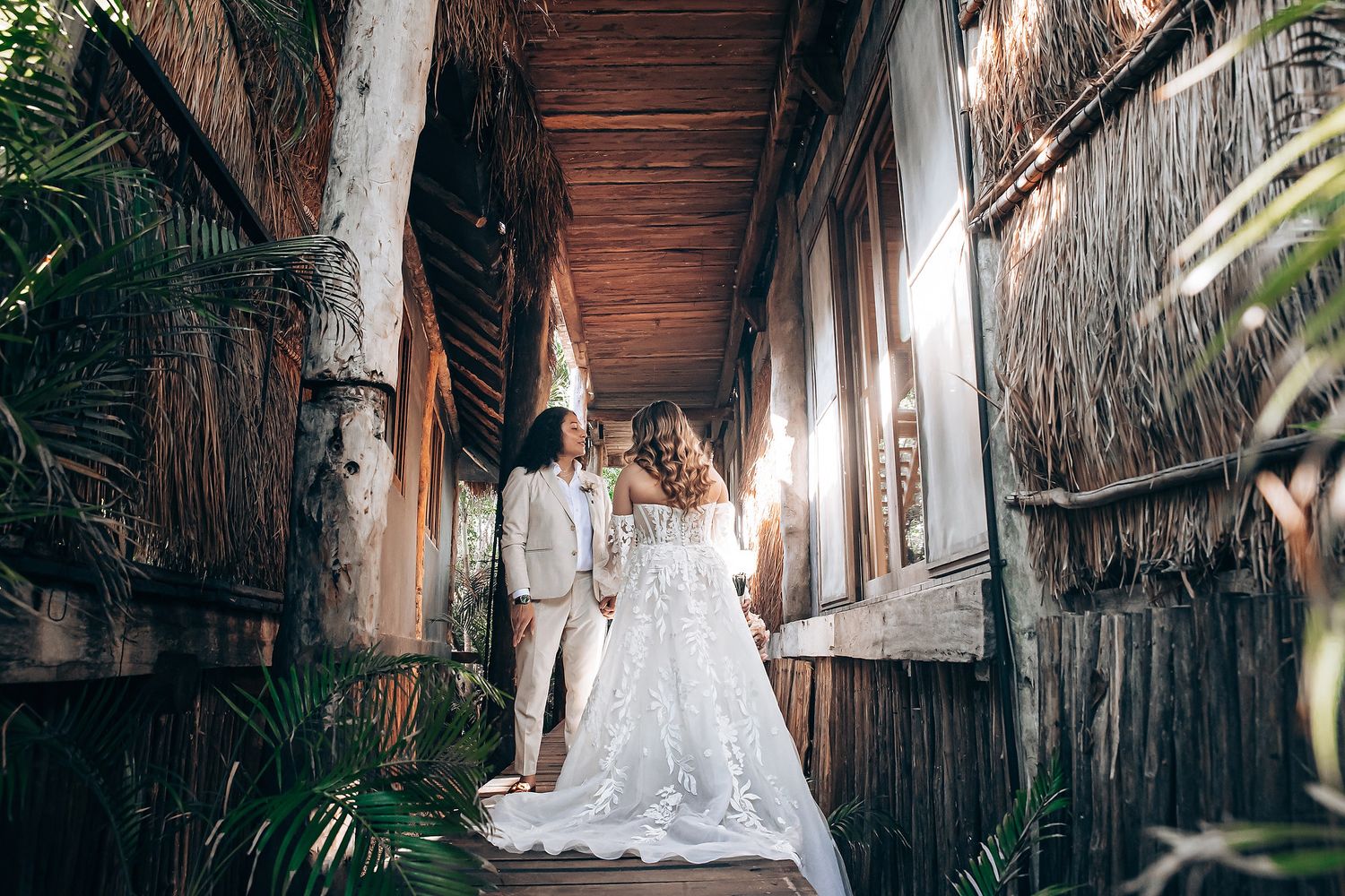 Wedding couple photographed against wooden walls and natural textures in a tropical setting.