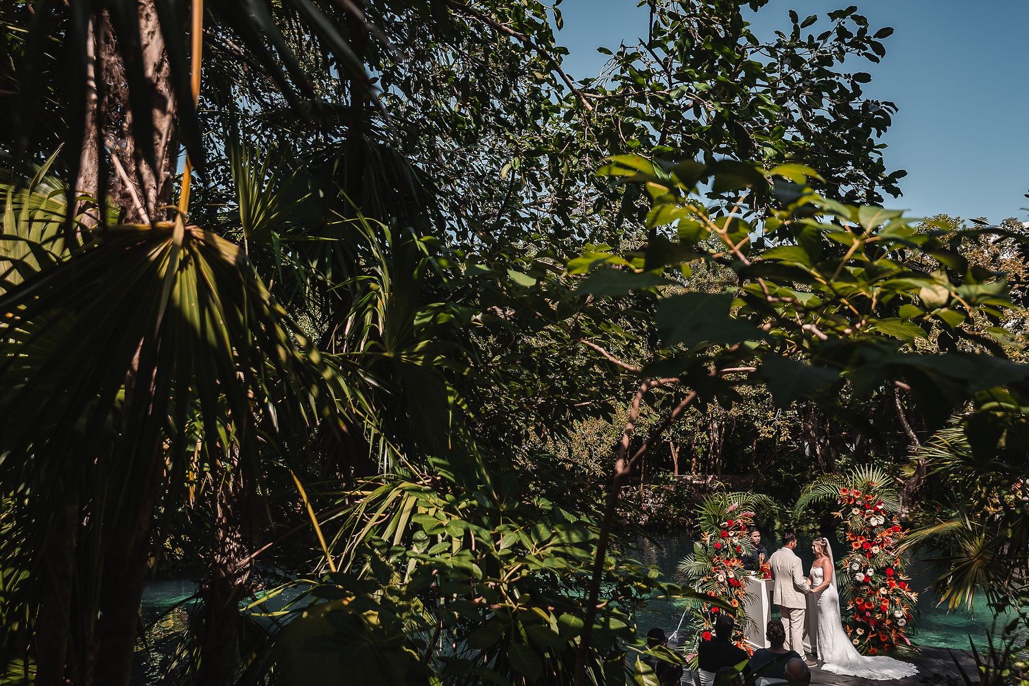 Tropical garden wedding ceremony with palm trees and natural water features.