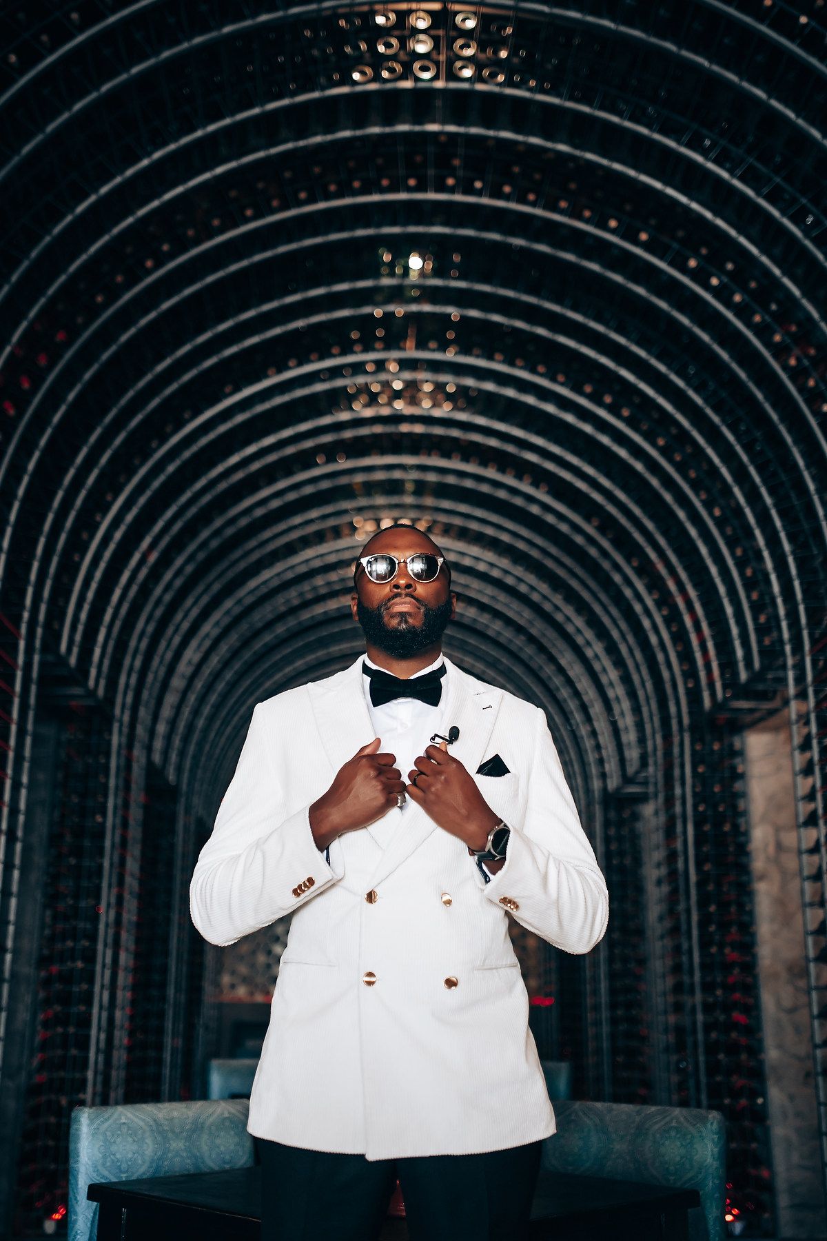 A series of dramatic portraits showing someone in a white suit and sunglasses against a dark tunnel background.