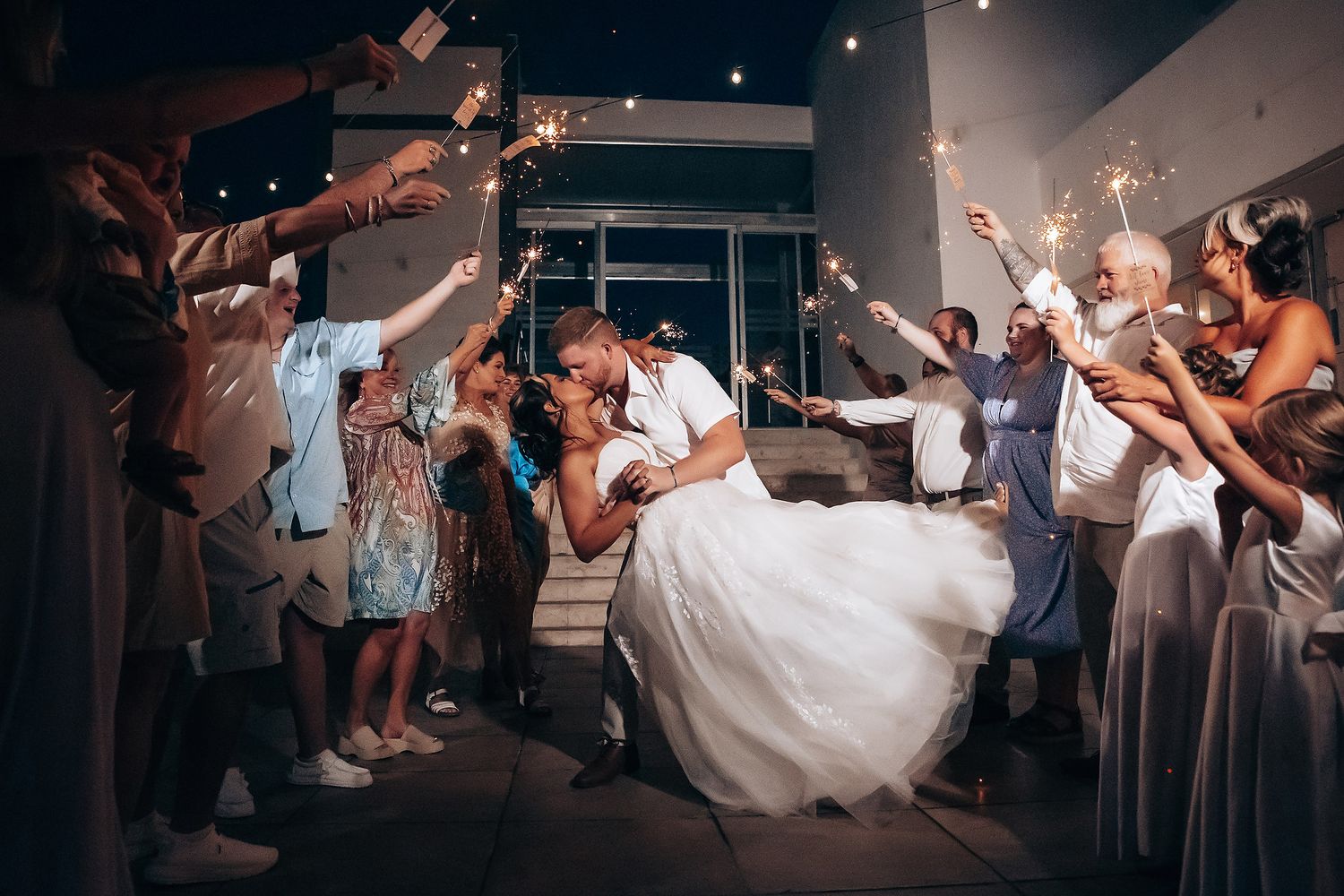 Wedding reception guests celebrate with sparklers as a couple shares a romantic dance moment.