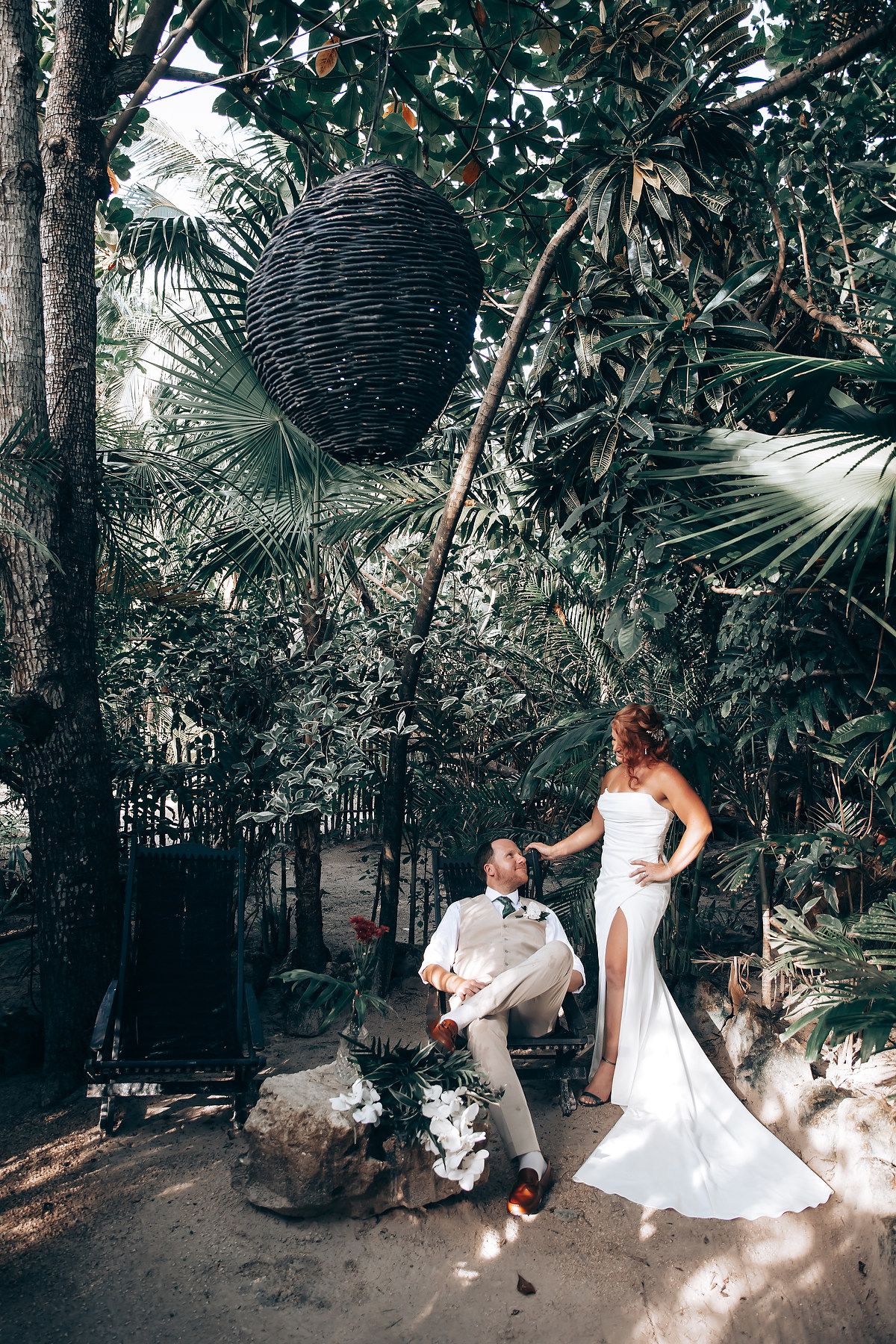 Playful wedding photoshoot with flowing white dress in a tropical garden path.