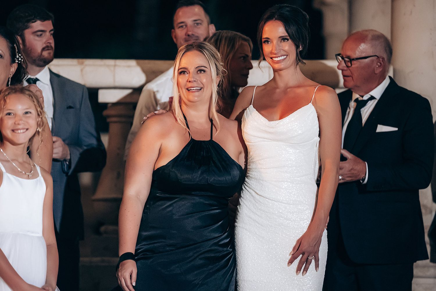 Wedding party members in formal attire gather together at an elegant indoor venue during a celebration.