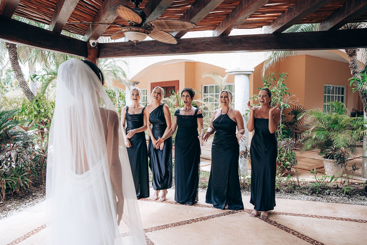 Wedding party in navy blue dresses and white gown pose together in an outdoor courtyard setting.