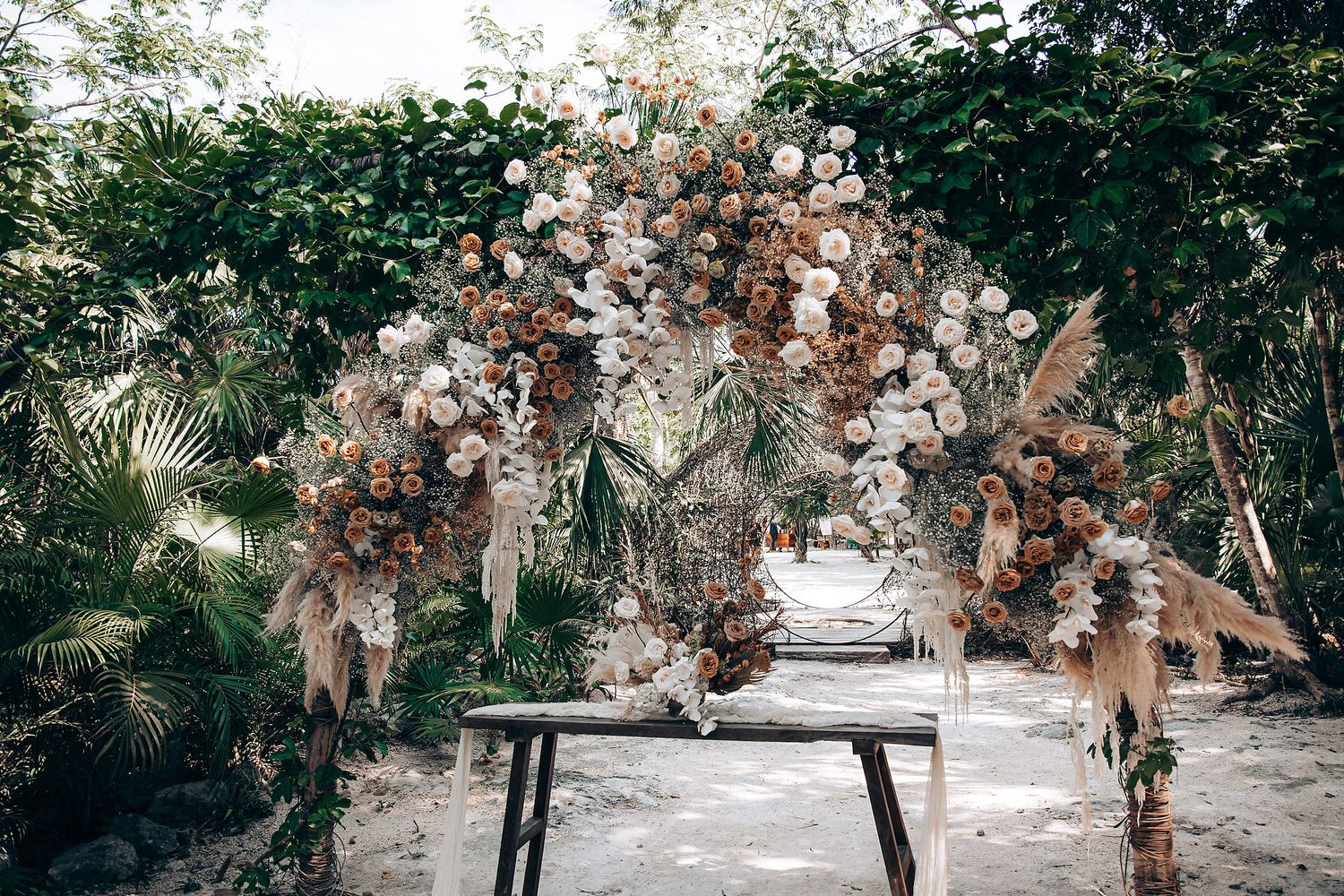A romantic outdoor wedding ceremony setup with white chairs and natural greenery in a garden setting.