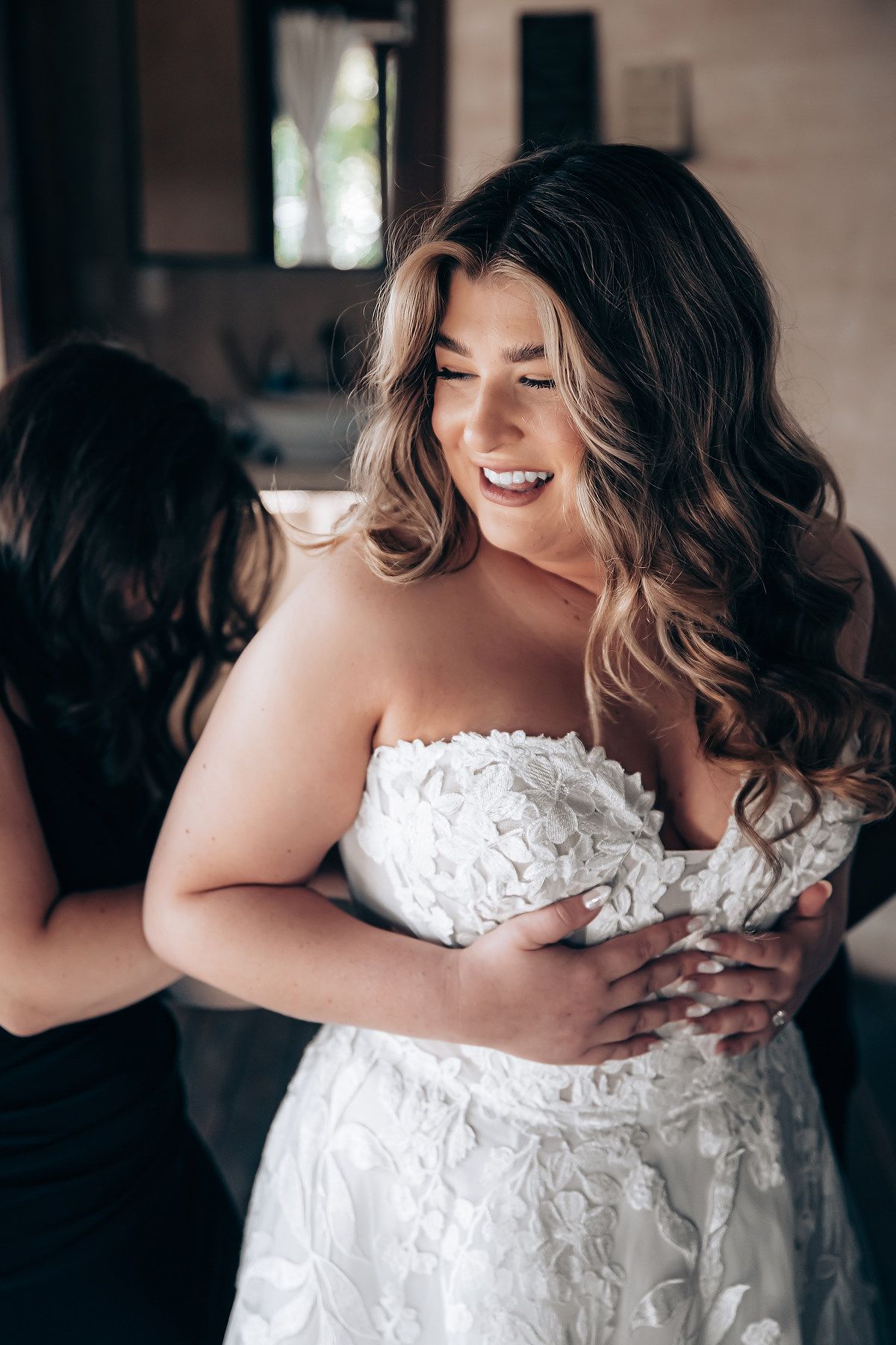 A joyful moment captured during the wedding dress preparation with helpers adjusting the gown.