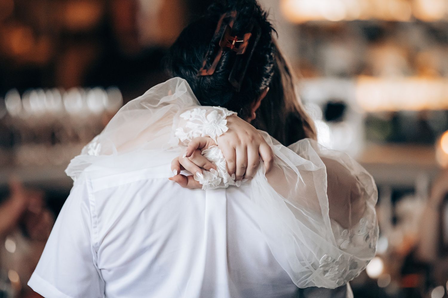 A person in a white dress holds a bouquet during a wedding ceremony in a warm-lit indoor venue.
