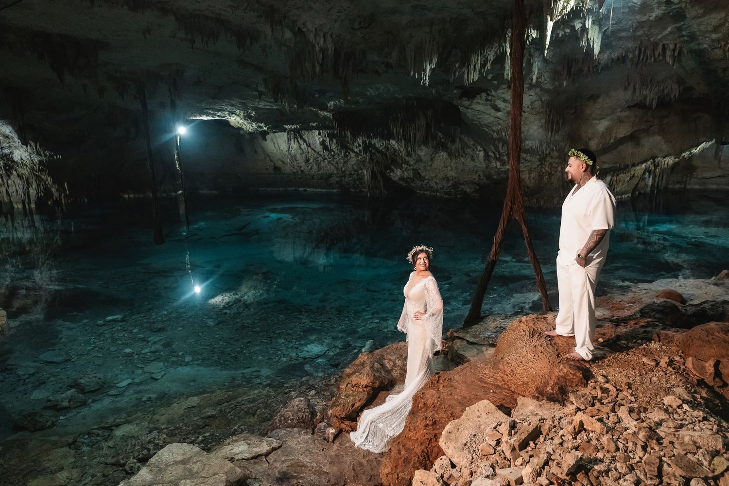 Ethereal blue-lit cave photography session with couple in white attire.