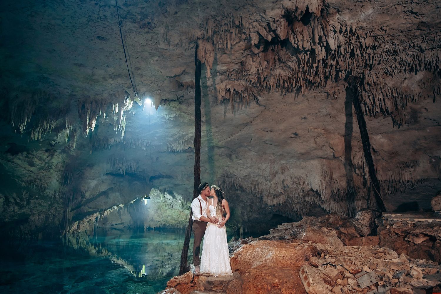 A mystical cave wedding ceremony with natural light beams illuminating the limestone cavern.