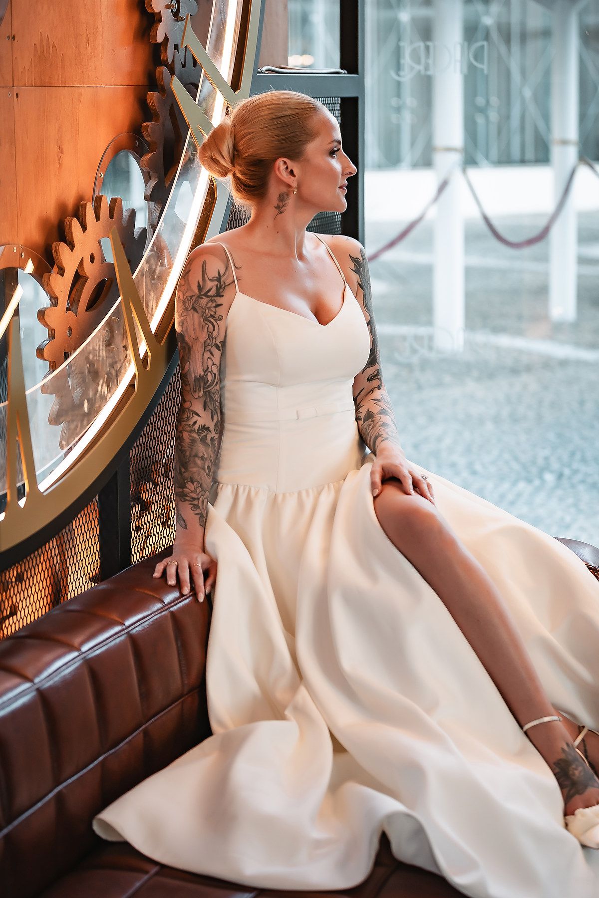 Elegant bridal portraits featuring a modern white wedding gown with tattoo details in an indoor setting.