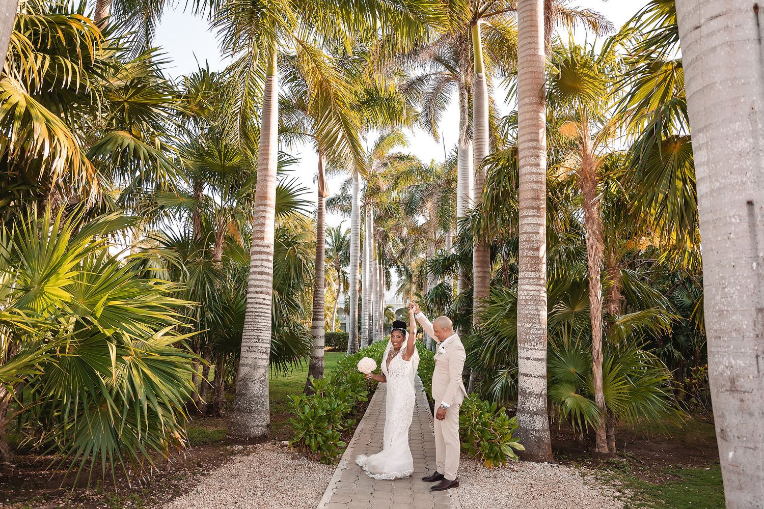 Row of tall palm trees line elegant white pillars in tropical garden setting.
