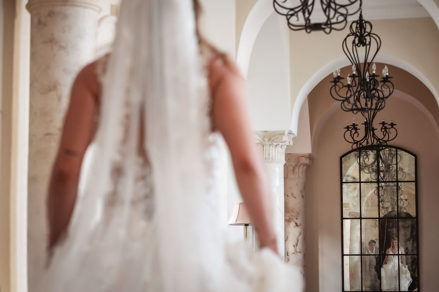 Elegant wedding photography featuring ornate iron chandeliers and arched doorways.