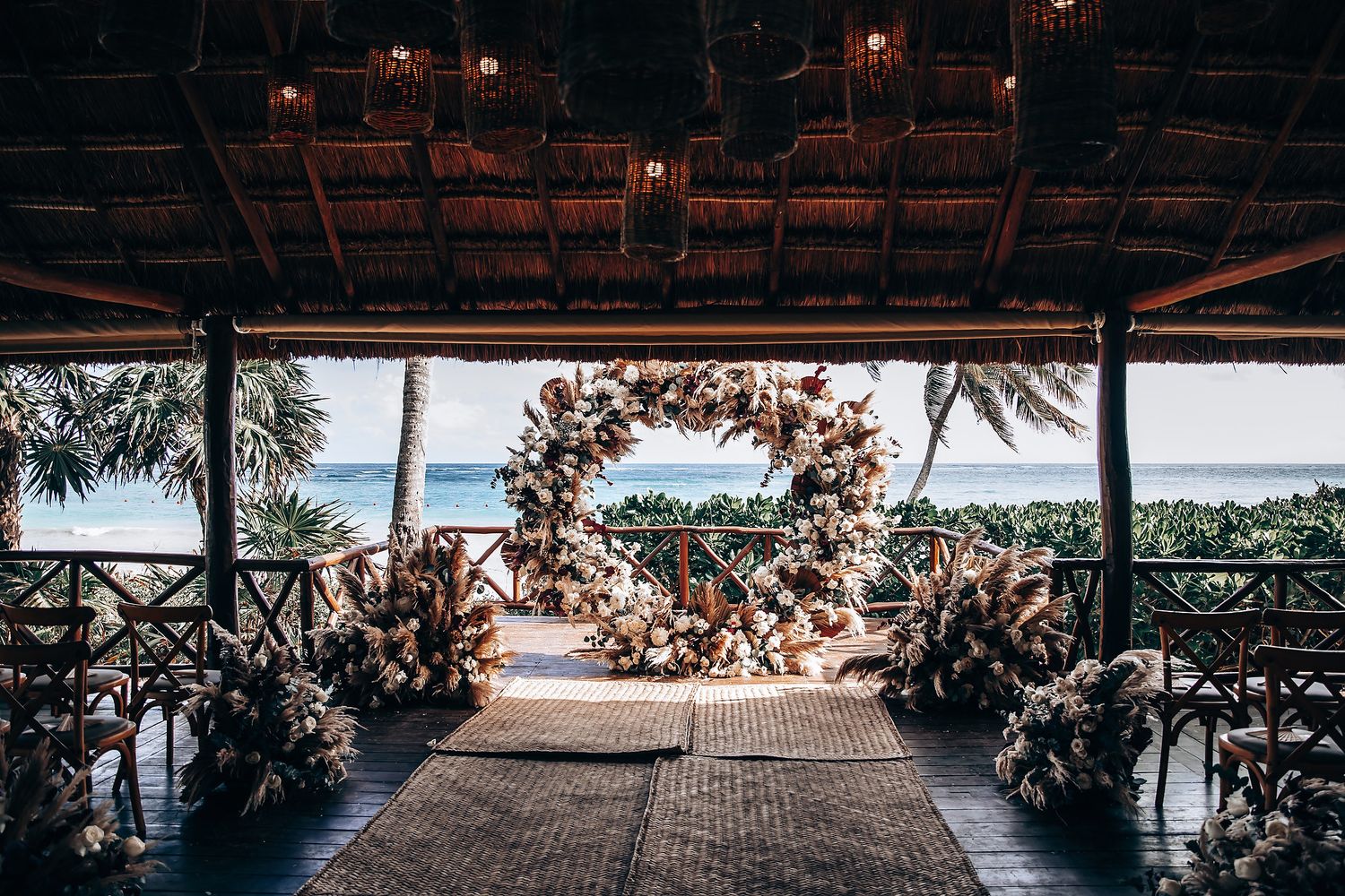 Panoramic view of an oceanfront wedding venue with palm trees and natural decor.