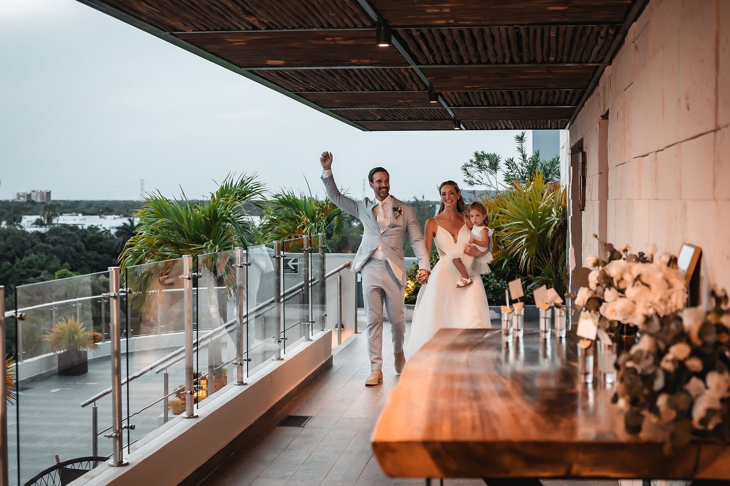 Celebratory moment on modern balcony overlooking water during wedding reception.