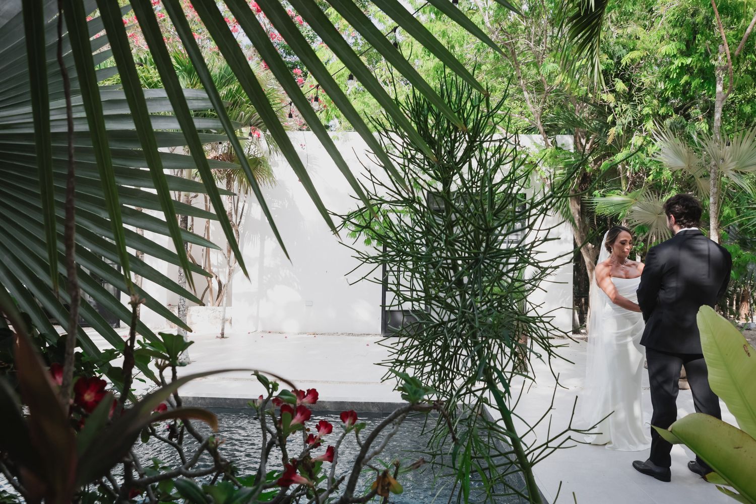 Bride and groom share intimate first look moment surrounded by lush tropical garden.