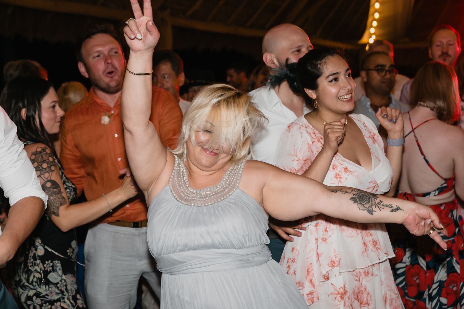 Joyful wedding guests dancing and celebrating on the dance floor at lively reception party.