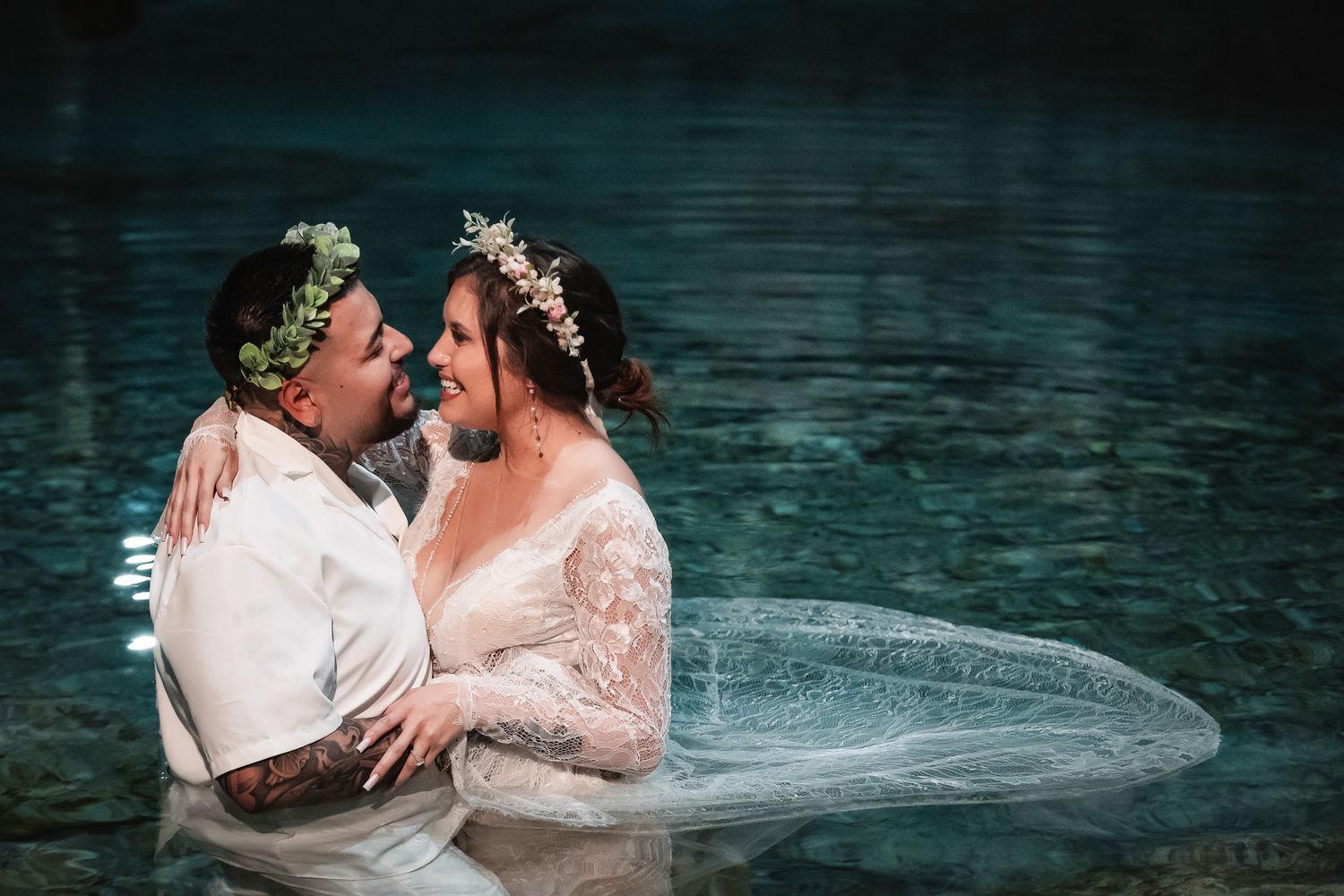 Bride and groom standing by turquoise water at Cenote Taak Bi Ha