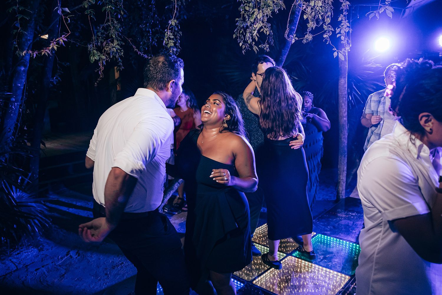 Outdoor dance party with blue lighting and LED floor creating an energetic nightclub atmosphere.