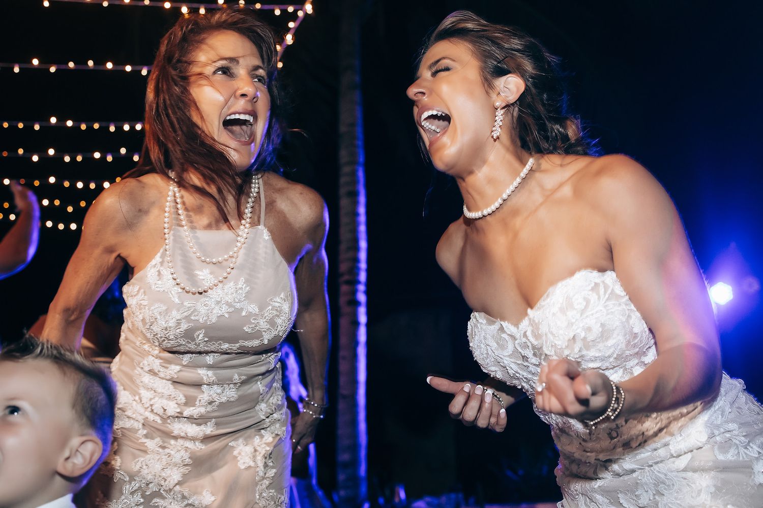 Wedding celebration with dancing and laughter under string lights at night.
