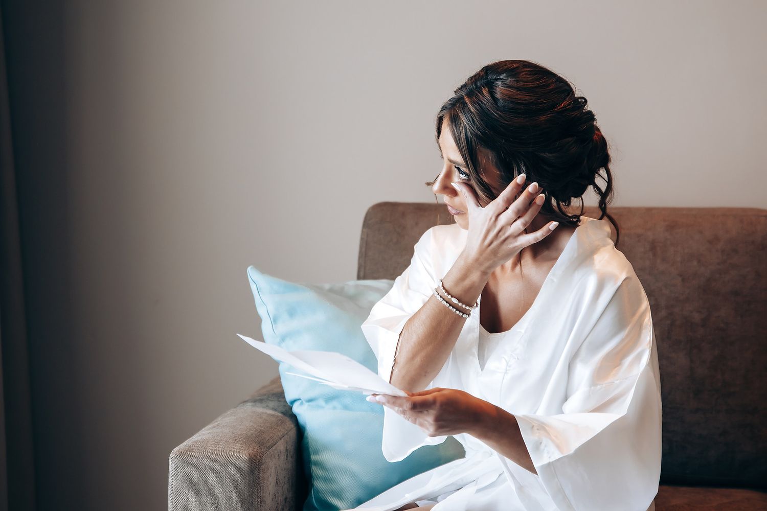 Person in white shirt sitting casually on a brown couch with blue pillows in a minimalist living room setting.