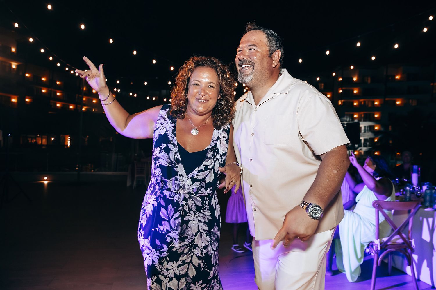 Couples dancing together at an outdoor evening celebration with string lights.