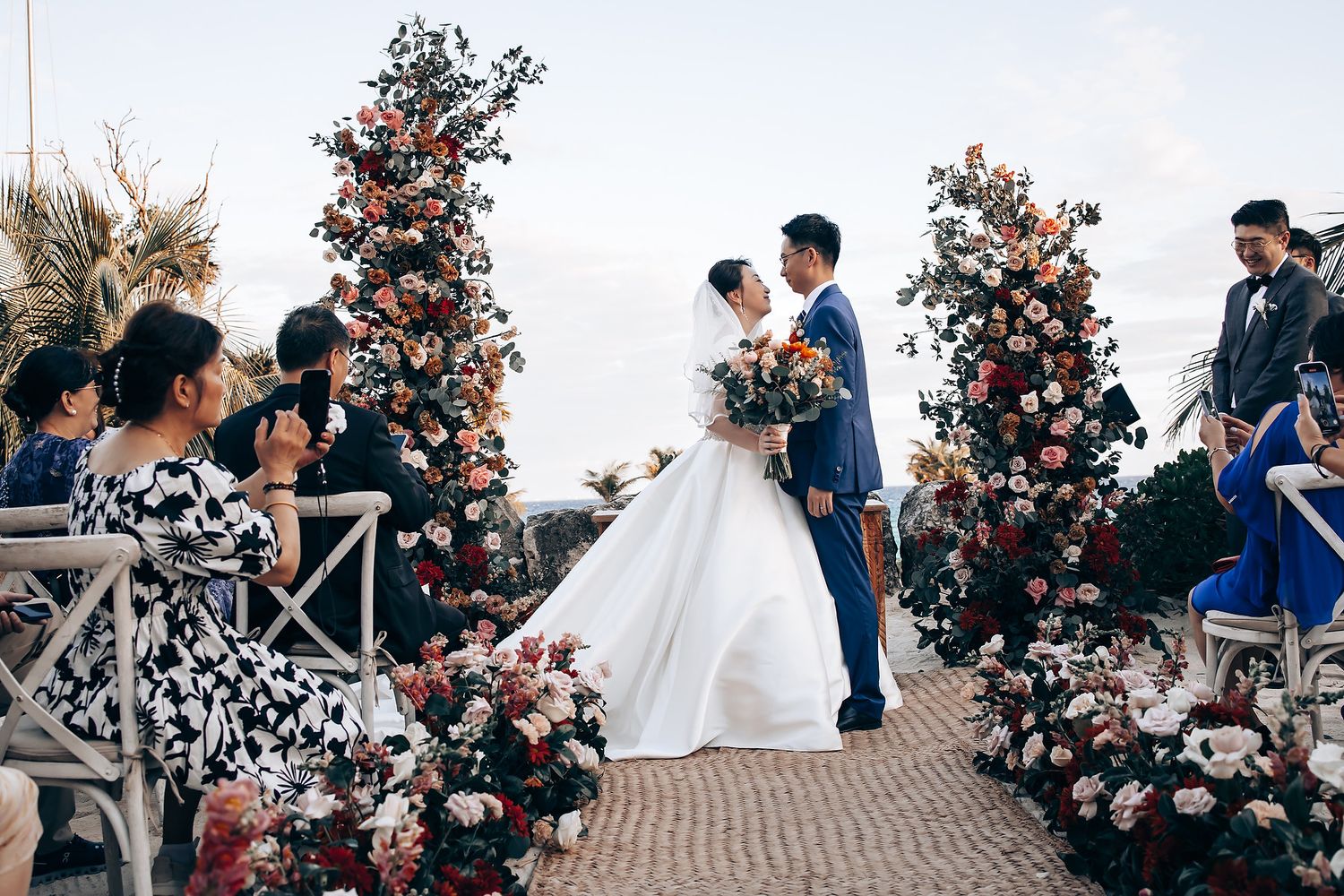 Wedding celebration at a beachside venue with decorative floral arrangements and palm trees.