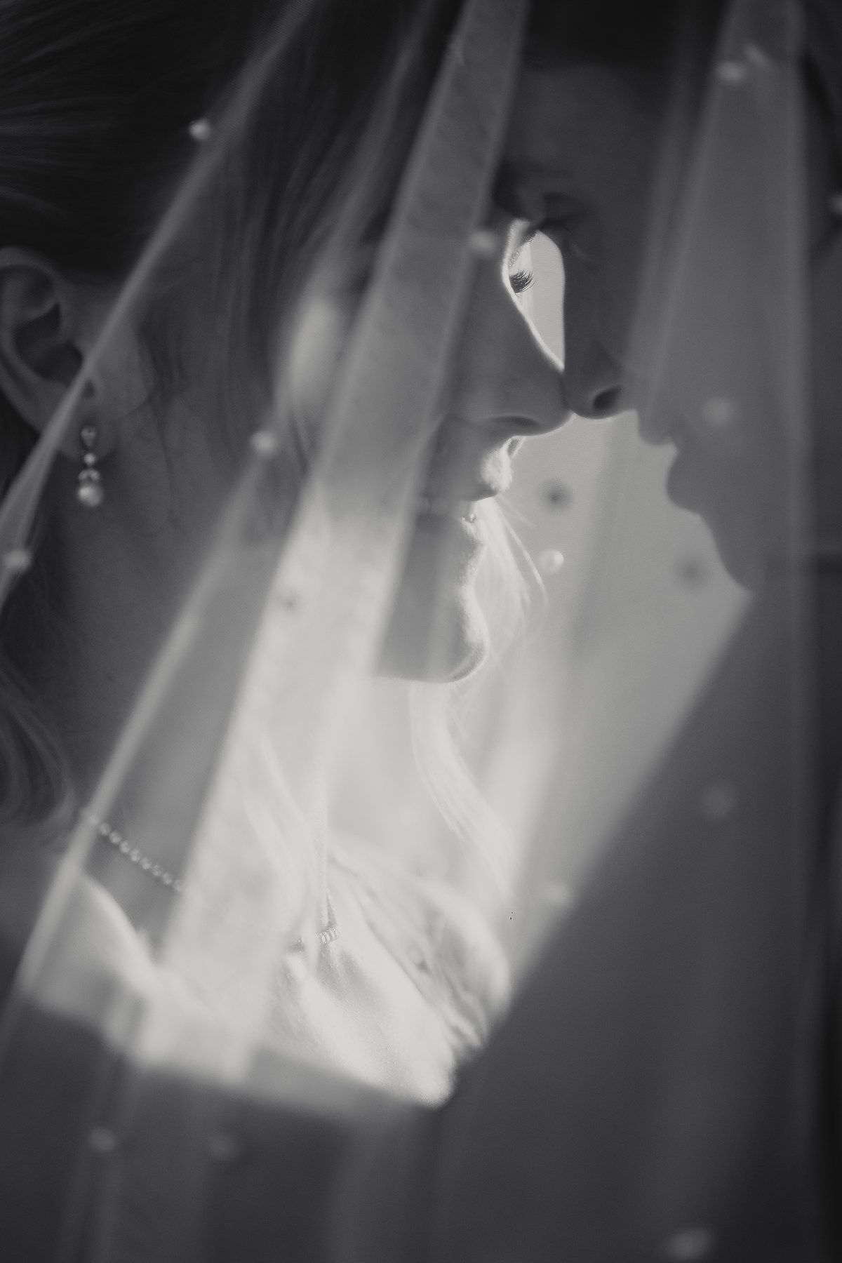 Black and white artistic wedding dress detail shot with flowing fabric and shadows.