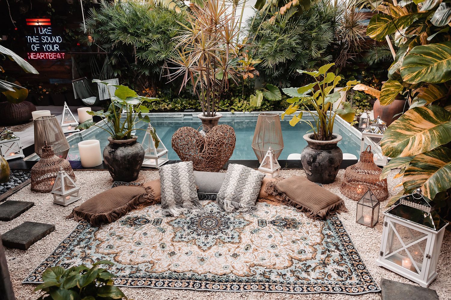 Outdoor garden setting with decorative stones and potted plants arranged around a pool area.