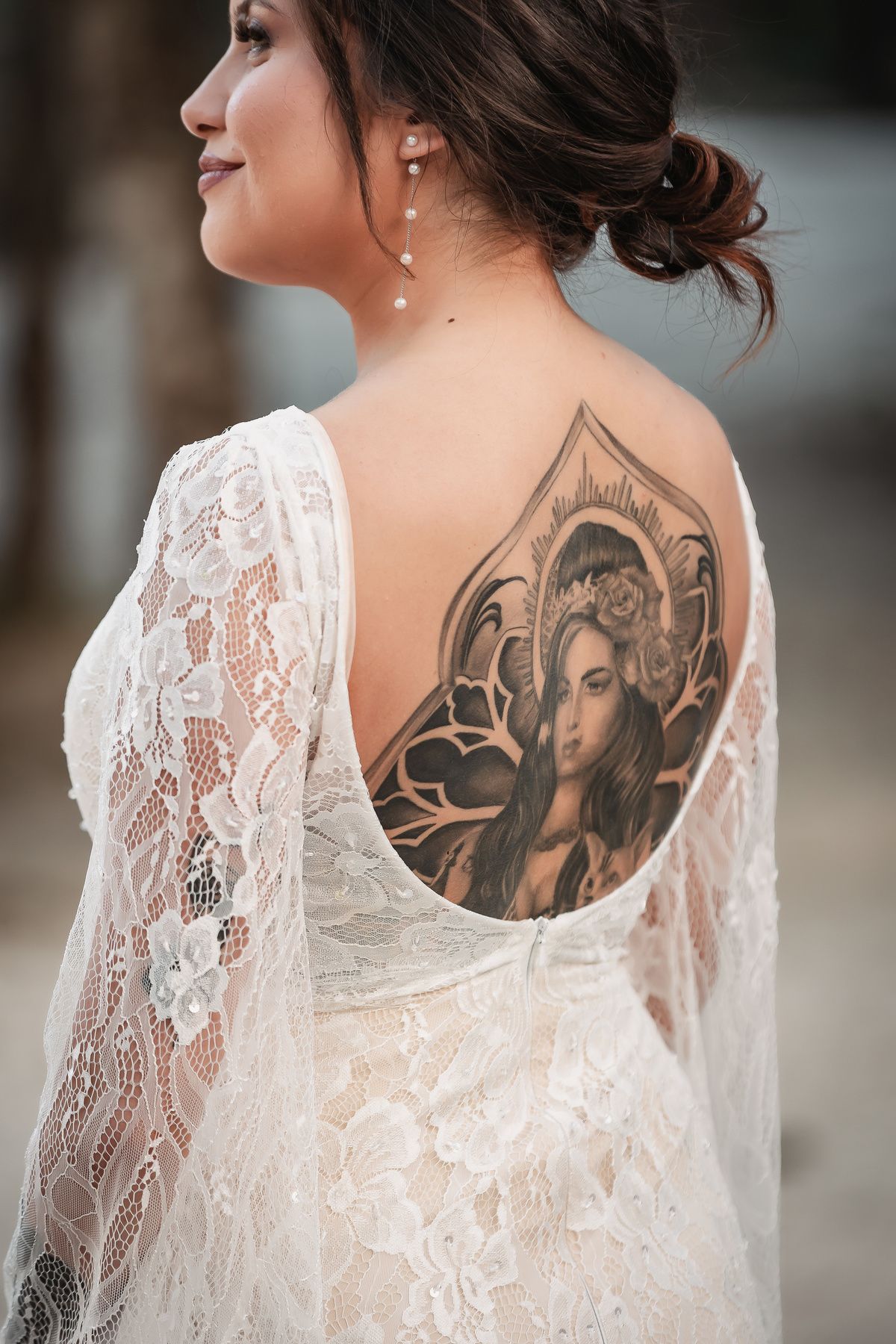 Close-up of a lace wedding dress revealing an intricate back tattoo design.