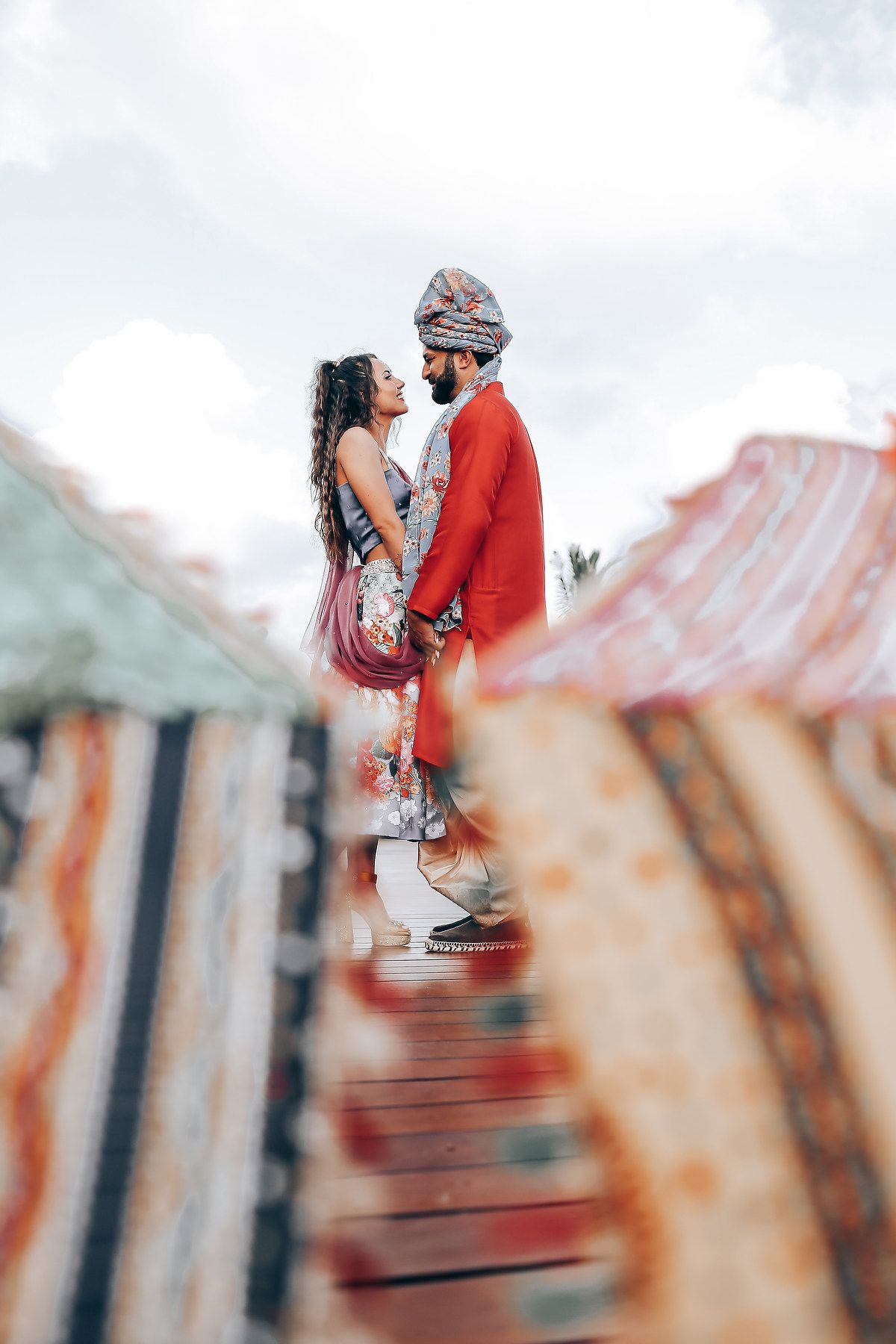 A couple shares a romantic moment on a rustic staircase with red and white striped railings in the background.