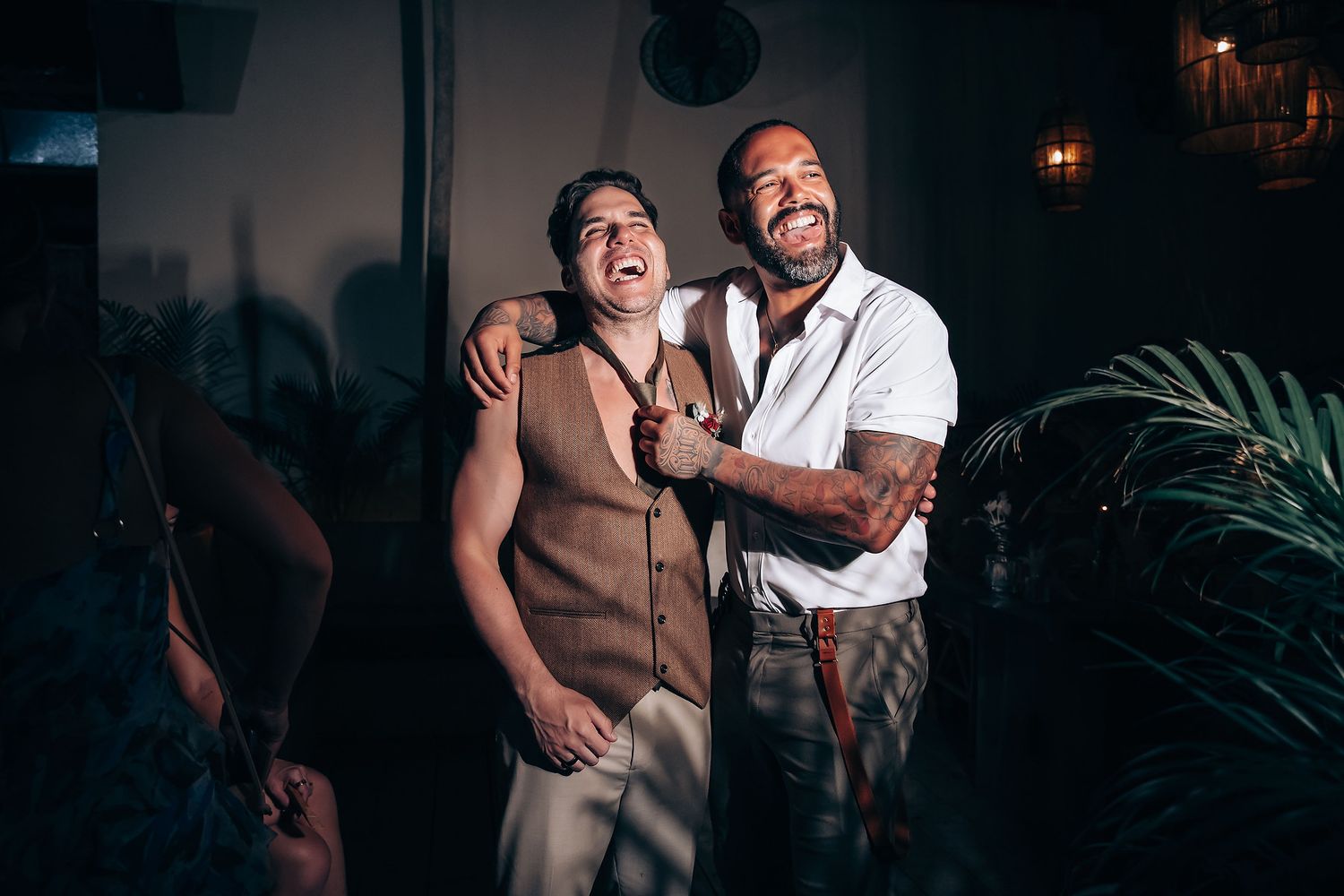 A couple shares joyful laughter together during a romantic evening celebration with warm lighting and elegant decor.