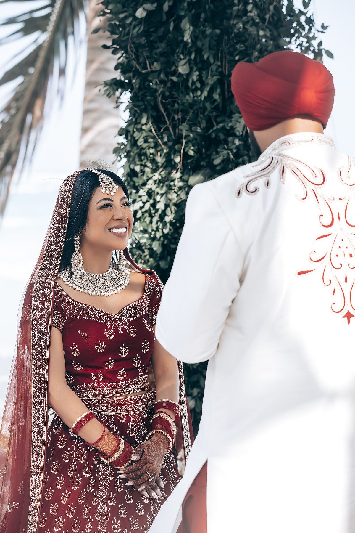 Elegant Indian wedding ceremony with traditional red bridal attire and beachside decor.