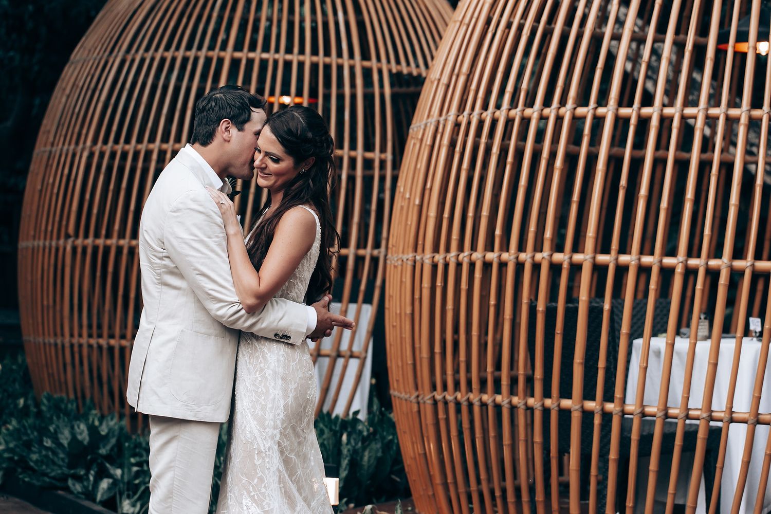 Intimate wedding portrait against large curved metal structures in an outdoor garden setting.