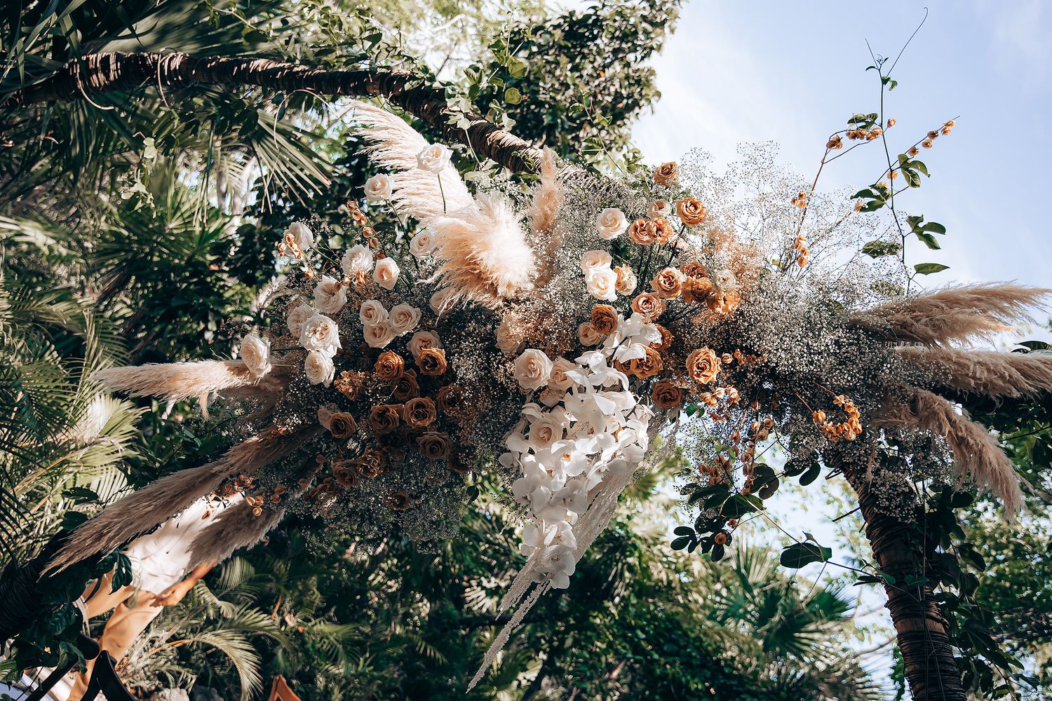 Dramatic overhead view of a dried flower arrangement with brown roses and wispy pampas grass against greenery.