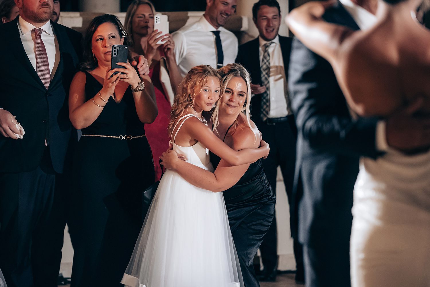 Wedding guests dance and celebrate together on the dance floor during a joyful reception celebration.