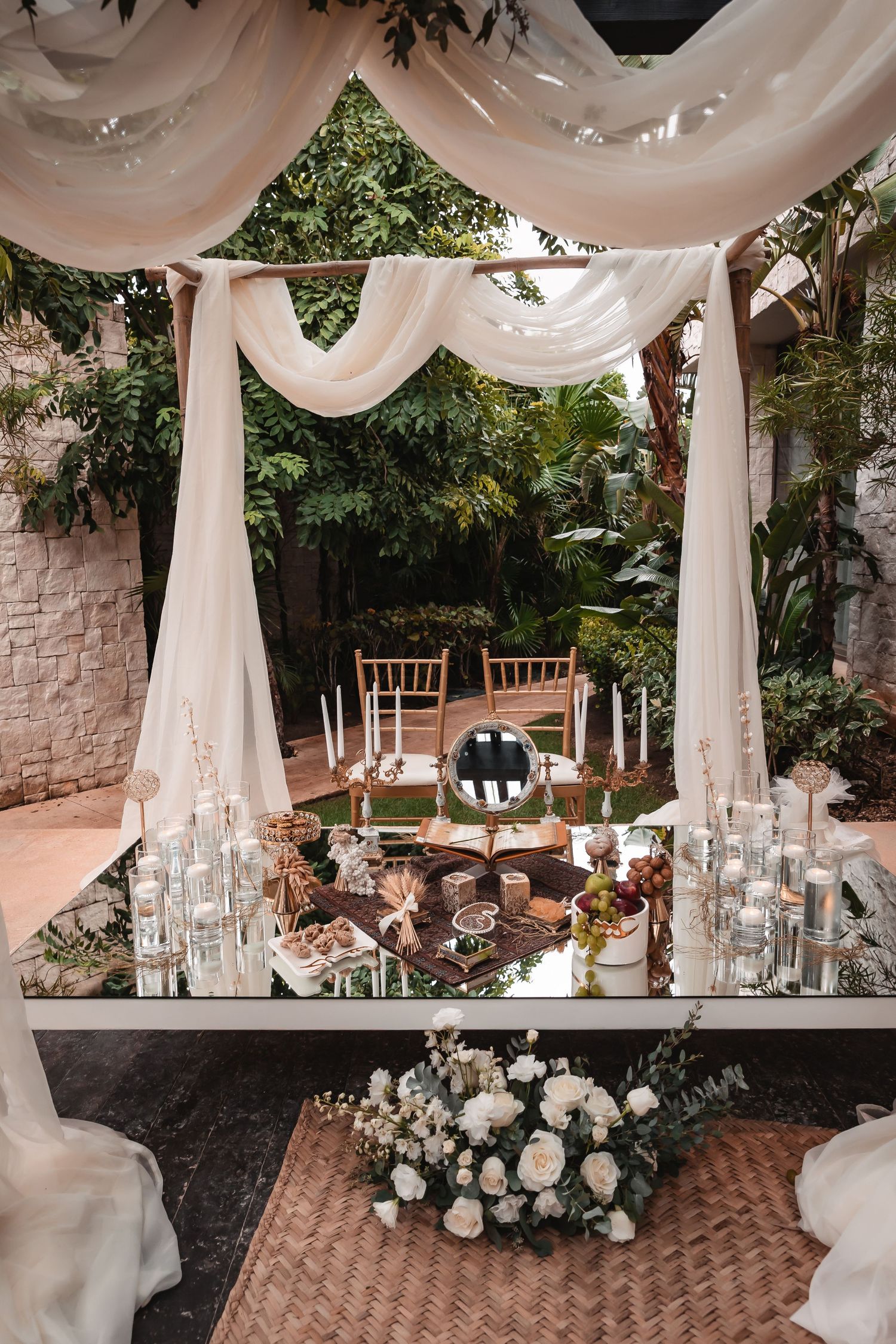 Elegant wedding reception setup with white draping, crystal glassware and floral centerpieces.