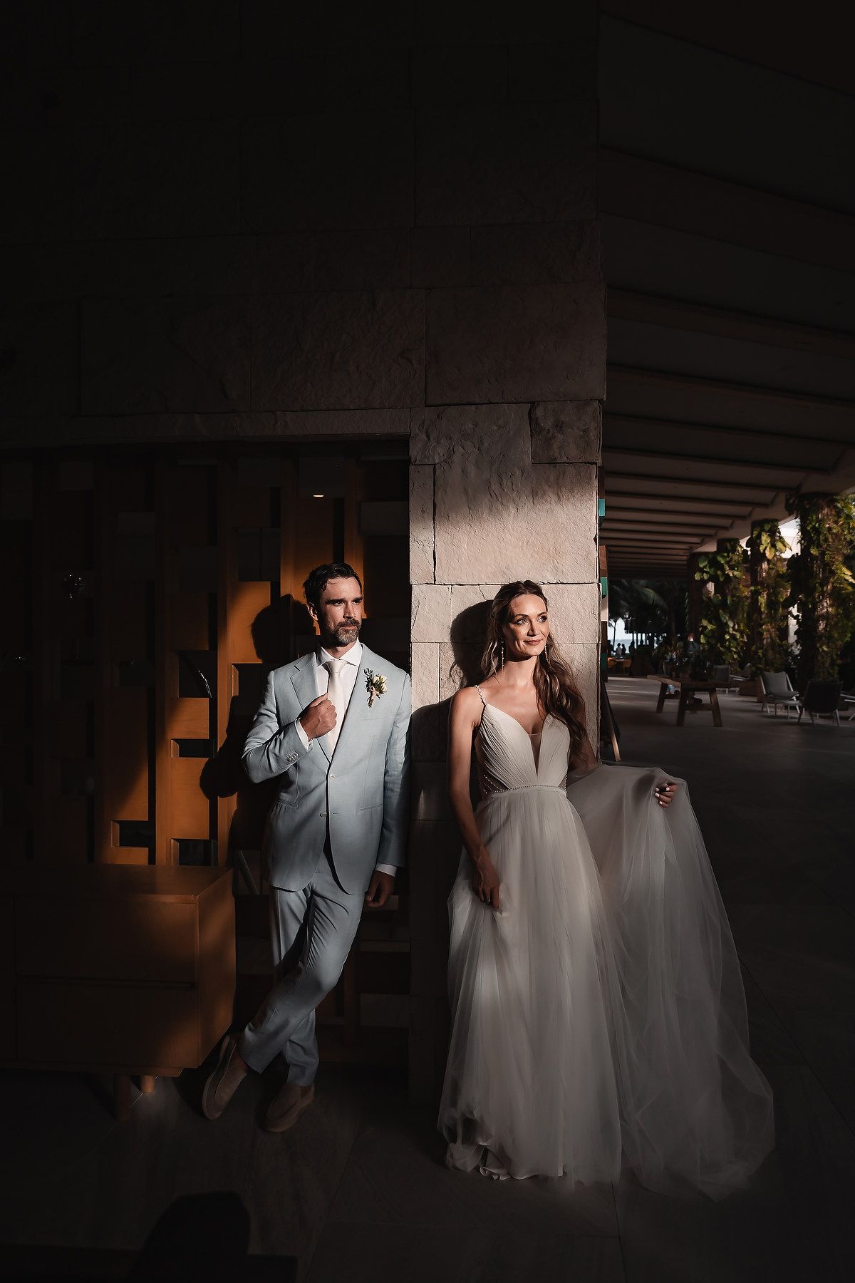 Dramatic low-light portrait of wedding couple in modern architectural setting.