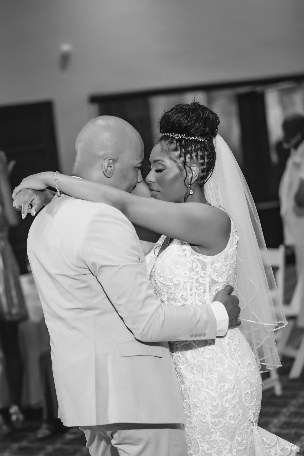 Black and white photo of a bride and groom sharing their first dance at a wedding reception.
