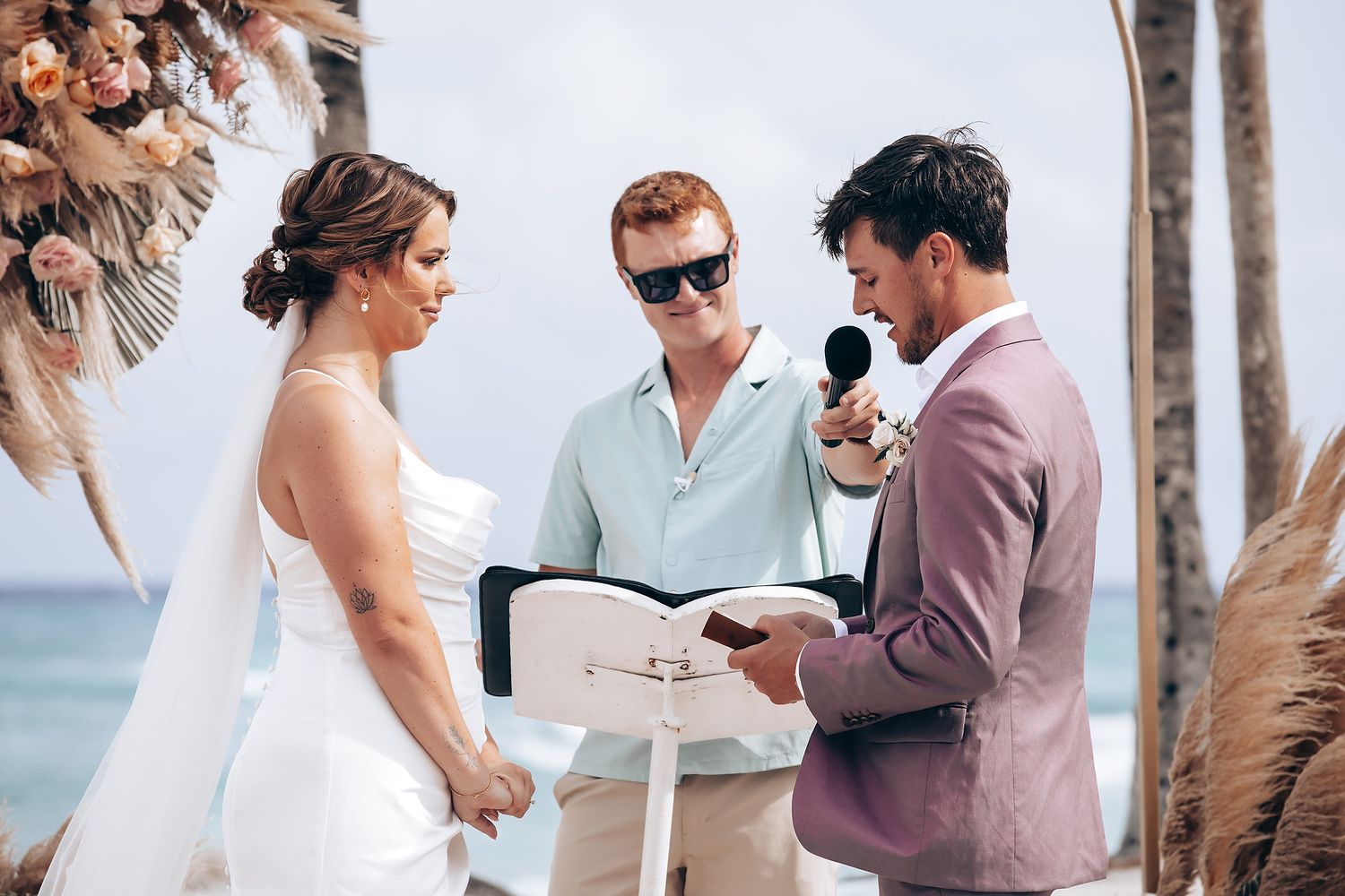Wedding guests mingling at outdoor beach reception with ocean view.
