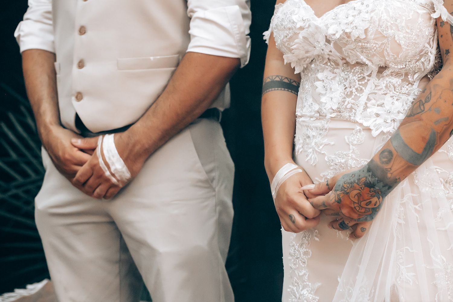 A wedding couple and their wedding party pose together in coordinated beige and white formal attire.