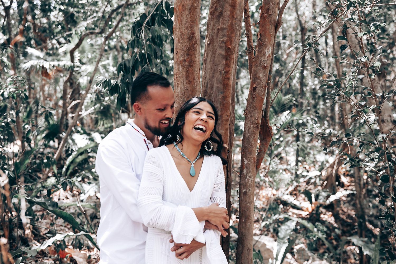 Intimate outdoor photoshoot in a wooded setting with white-clad figures.