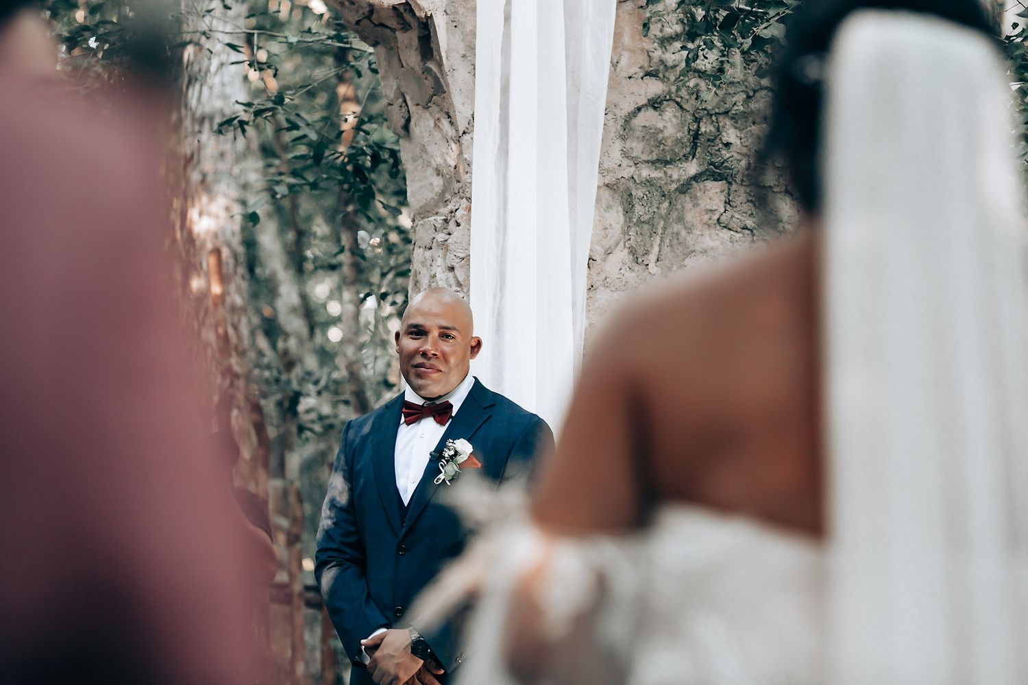 An emotional moment captured during an outdoor wedding ceremony with stone walls and greenery.